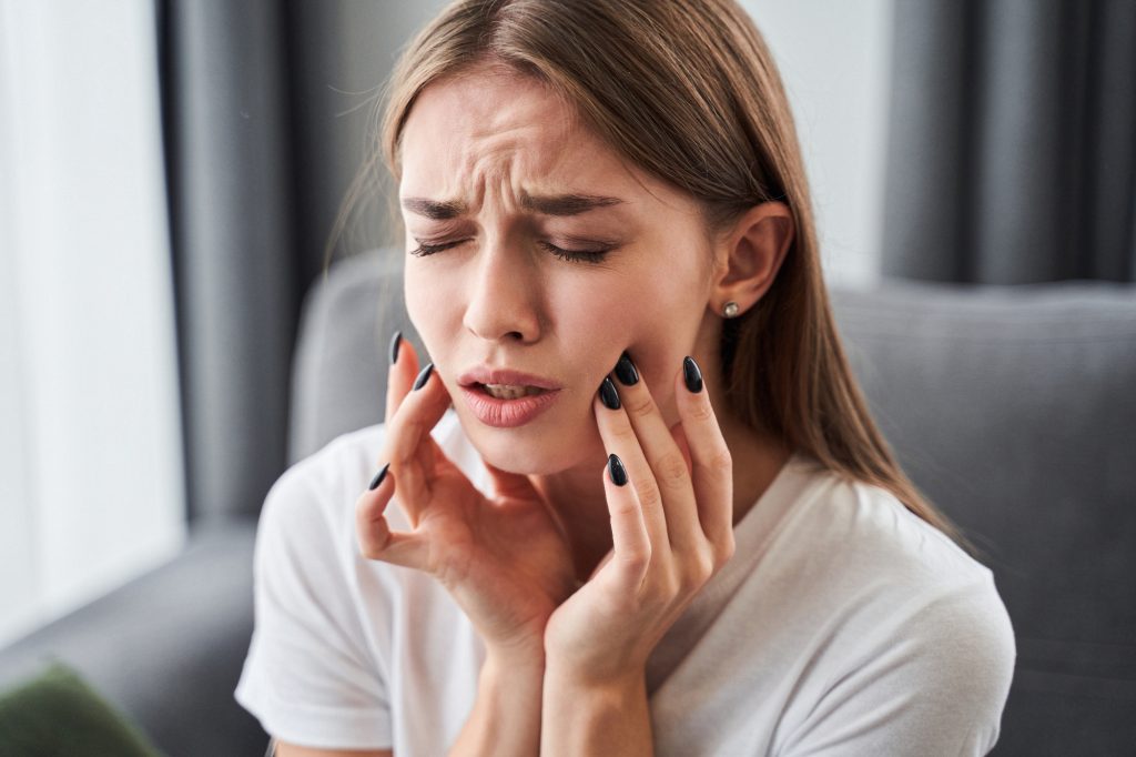 Woman experiencing toothache, holding her jaw.