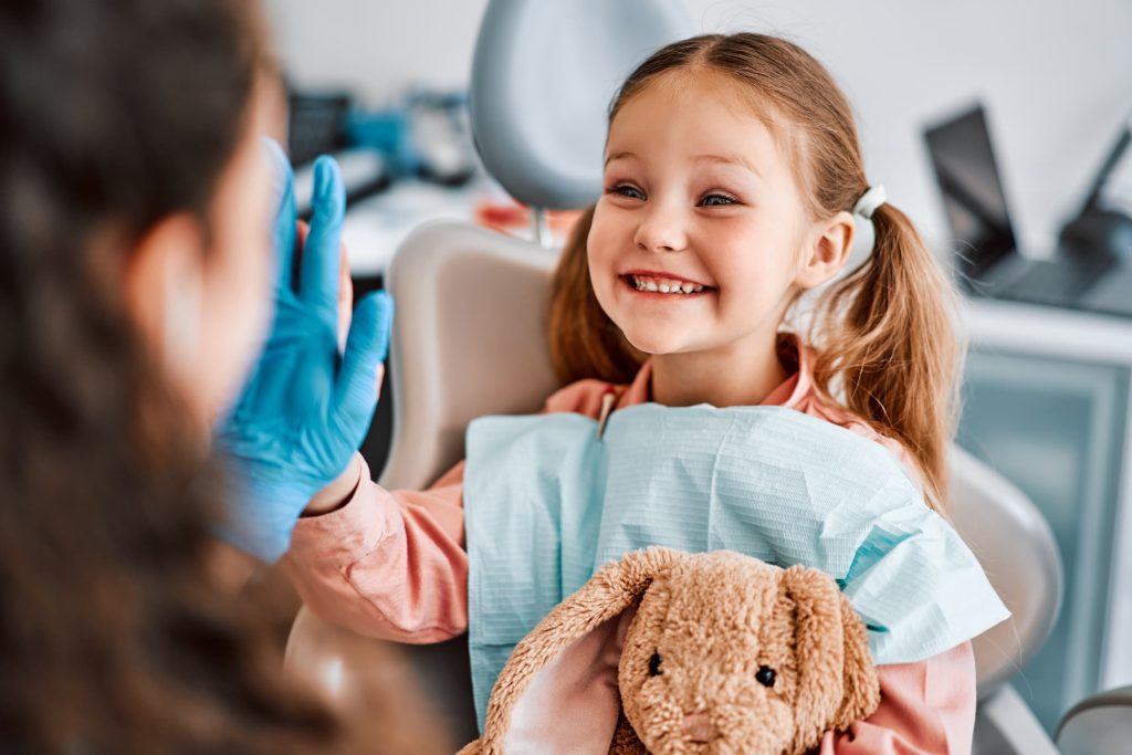 Smiling child with dentist and teddy bear.