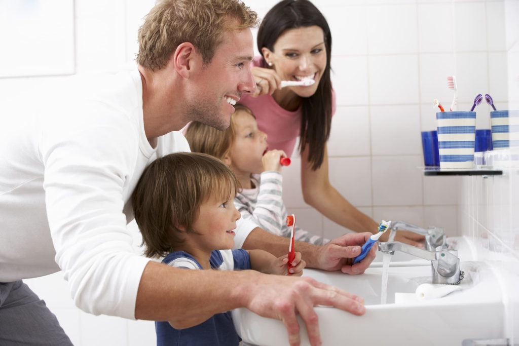 Family brushing teeth together in bathroom