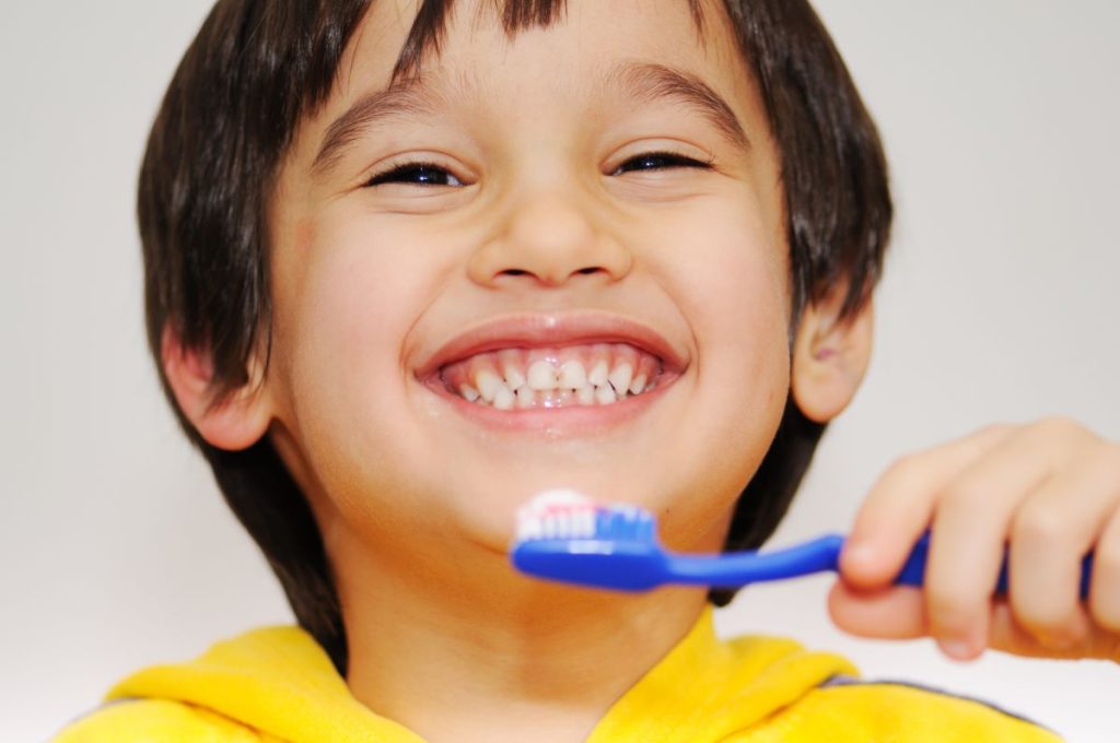 Smiling child holding a toothbrush.